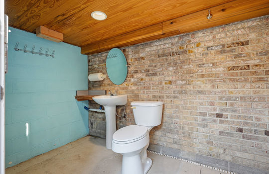 additional bathroom, concrete flooring. toilet, sink, brick feature wall, wood ceiling