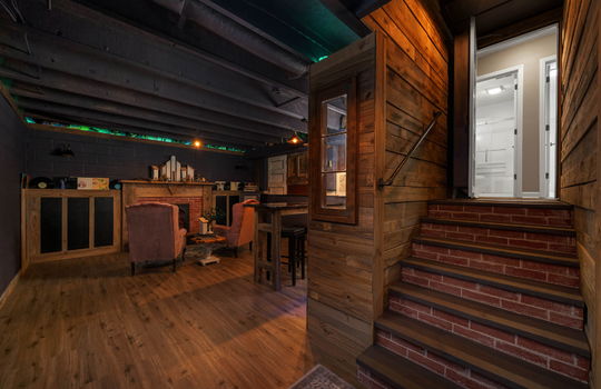 basement level speakeasy space, stairs, luxury vinyl flooring, fireplace, basement