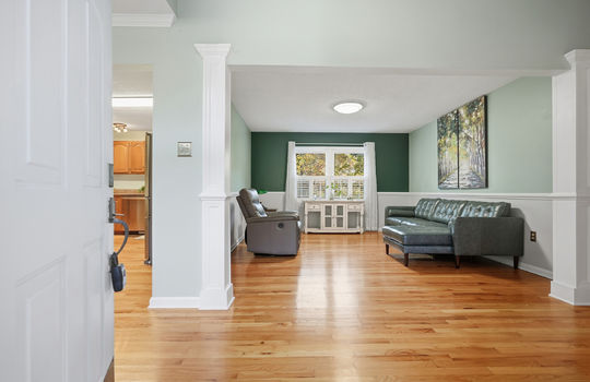 entryway, hardwood flooring, view into living area, windows, partial view of kitchen