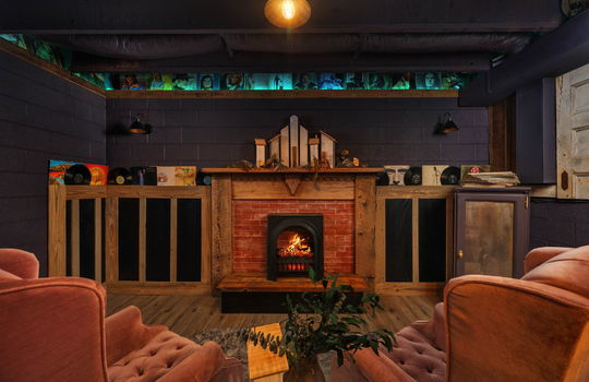 lower level speakeasy space, luxury vinyl flooring, fireplace, block walls,