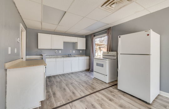 kitchen, luxury vinyl flooring, refrigerator, electric range, cabinets, countertops, sink, window, fluorescent lighting, ceiling tiles