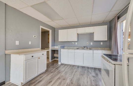 kitchen, luxury vinyl flooring, cabinets, countertops, sink, electric range, windows, doorway to bathroom