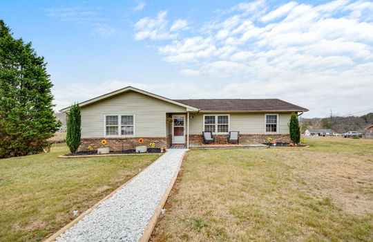 Ranch style home, vinyl siding, gravel sidewalk, front door, front yard, landscaping, trees