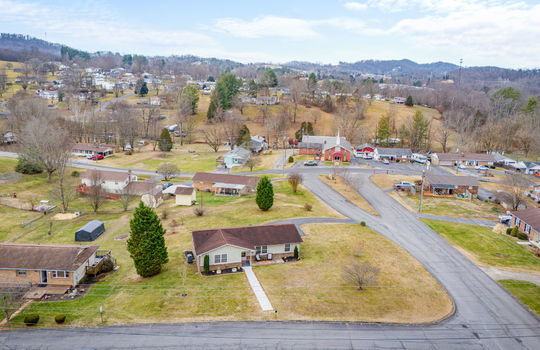 aerial view of home, front yard, gravel sidewalk, ranch style home, back yard, driveway, road, neighboring homes