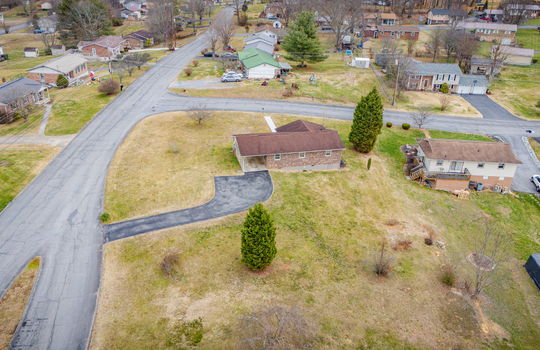 aerial view of home, back yard, driveway, carport, front yard, road, neighboring homes