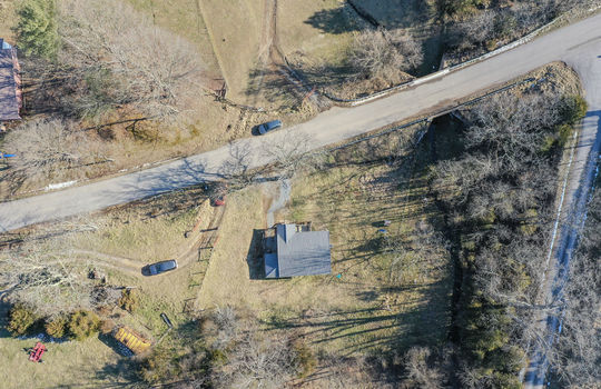 overhead aerial view of property, road, front yard, back yard, roof, trees, neighboring home/properties