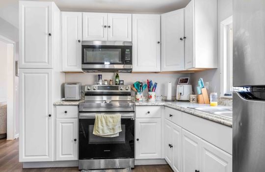 kitchen, white cabinets, stainless appliances, stove, microwave, refrigerator, sink, window above sink, laminate countertops