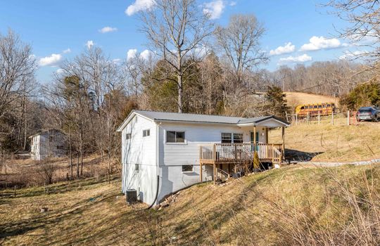 front of home, front porch, covered front porch, front door, vinyl siding, trees, side yard, nearby homes/properties