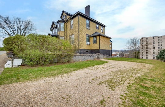right side view of home, Victorian Home, wood siding, hedge, block wall, gravel driveway