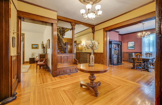 formal entry/foyer, hardwood flooring, built in bench, ornate wood trim, chandelier, stairway, hallway