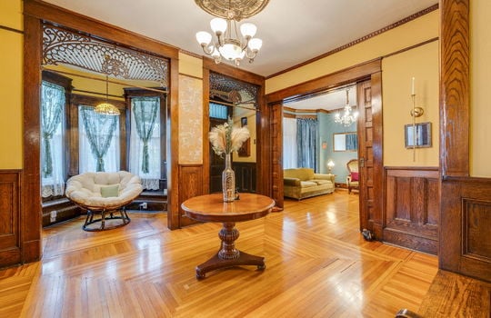 foyer, entryway, reading nook, bay window, front door, hardwood flooring, ornate wood trim, chandelier