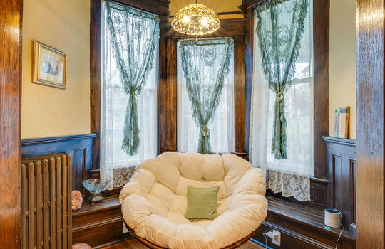 entry nook, window bench, radiator, bay window, chandelier, hardwood flooring, wood wainscoting,