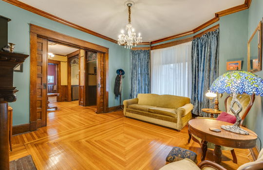 formal living room, wood pocket doors, hardwood flooring, bay window, chandelier, wood trim, fireplace