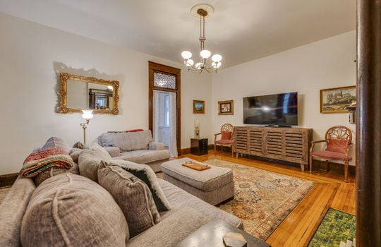 Den, hardwood flooring, wood trim, transom windows, chandelier