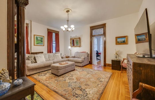 den, hardwood flooring, wood trim, transom window, windows, chandelier, fireplace