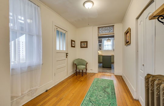 wide hallway to kitchen, exterior door, hardwood flooring, transom window, storage closet