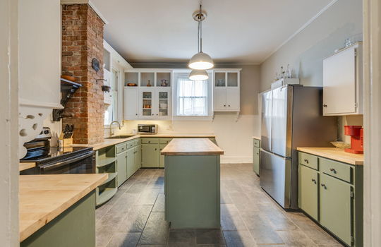 kitchen, tile flooring, cabinets, butcher block countertops, kitchen island, sink, refrigerator, range, brick feature