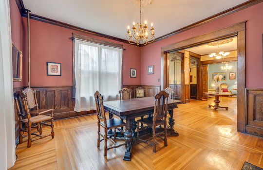 formal dining room, wood trim, wood wainscoting, pocket doors, chandeliers, hardwood flooring, windows
