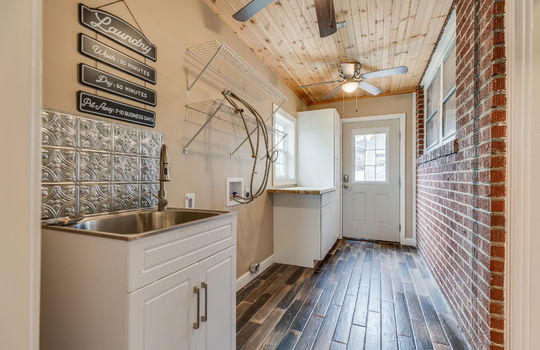 laundry room, washer/dryer hookups, brick wall, exterior door, utility sink, cabinets