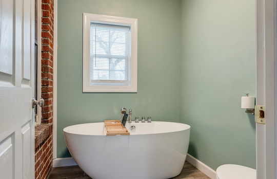 bathroom, tub, toilet, brick wall, wood ceiling