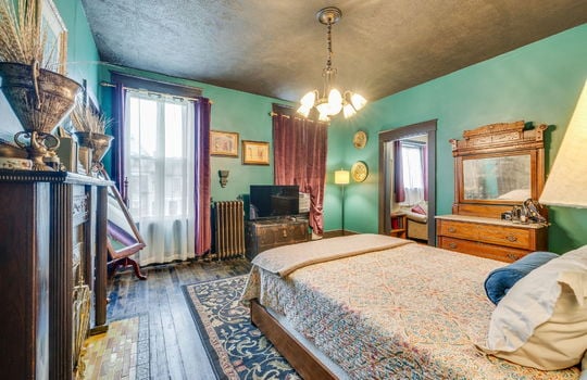 bedroom, wood flooring, fireplace, wood mantle, wood tile, windows, chandelier