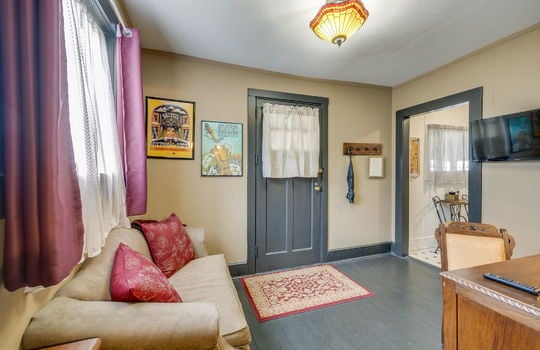 living room, hardwood flooring, private entry door, doorway to kitchenette