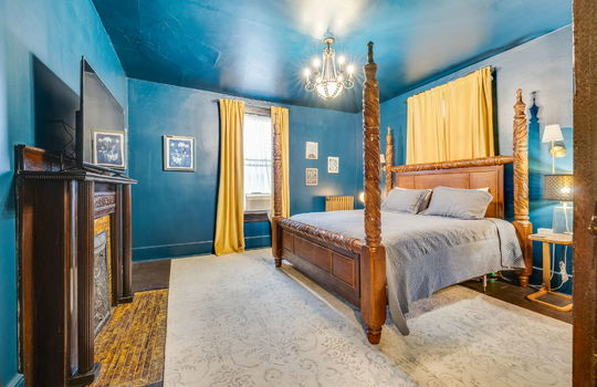 bedroom, hardwood flooring, fireplace, wood mantle, windows, chandelier