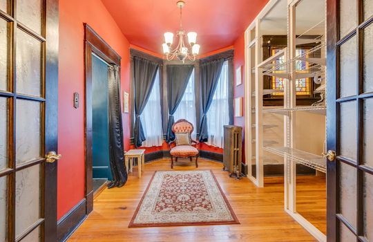 closet, sitting area, bay window, shelving, stained glass window, radiator, doorway into primary bedroom