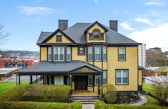 victorian home, two story home, wrap around porch, double front door, stained glass window, wood siding, hedges