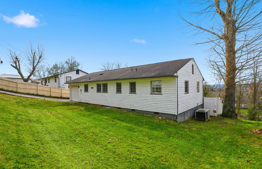 one level home, ranch style home, vinyl siding, garage, garage door, driveway, fencing, trees, heat pump