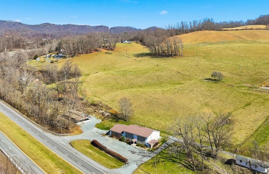 aerial view of veterinary office and land, mountain views, surrounding properties, parking lot, barn