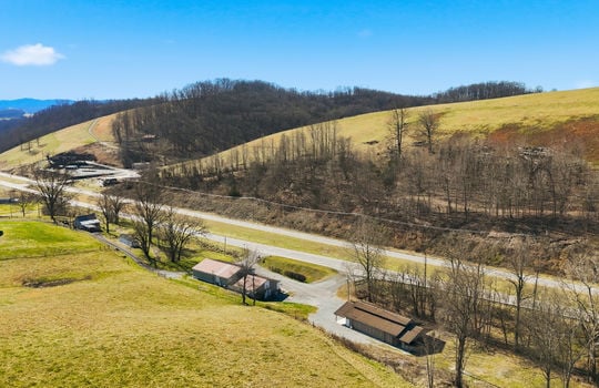 aerial view of veterinary office and land, mountain views, surrounding properties, parking lot, barn, highway