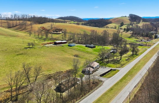 aerial view of veterinary office and land, mountain views, surrounding properties, parking lot, barn, highway