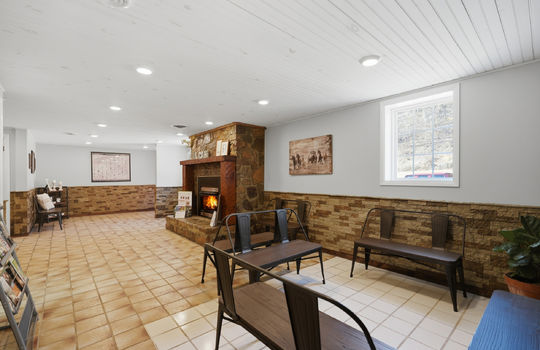 reception/waiting area, stone fireplace, tile flooring, windows, recessed lighting, stone wall design