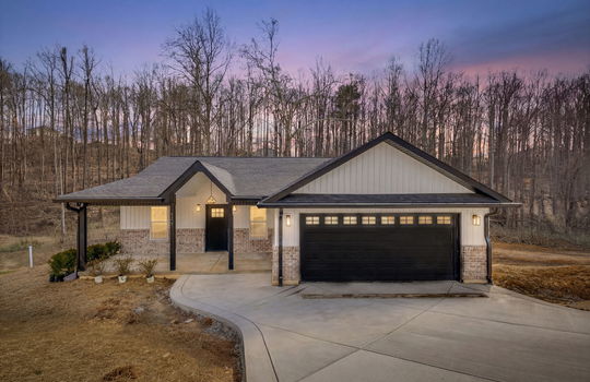 twilight photo, new construction home, brick, vinyl siding, attached garage, covered front porch, front door, concrete driveway, yard, landscaping