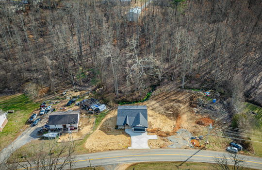 aerial view of home, driveway, new construction home, creek, trees, neighboring homes