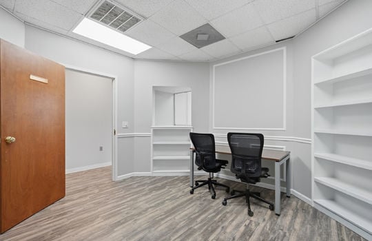 office, luxury vinyl flooring, fluorescent lighting, built-in shelving, decorative trim, reception window
