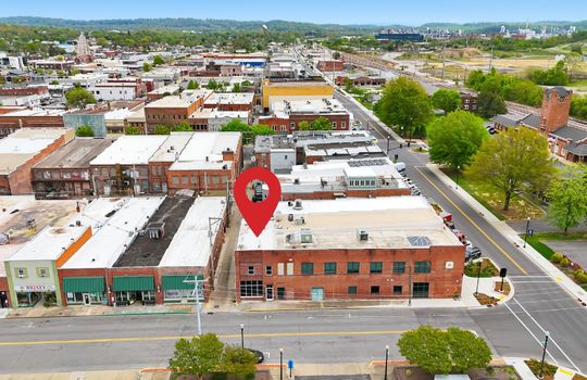 aerial view of commercial space for lease, location pin, main street, road, nearby businesses, mountain views, railroad, street parking
