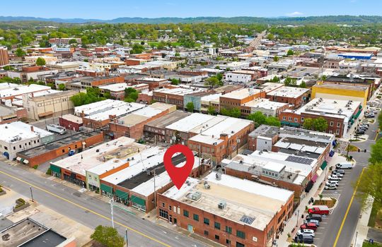 aerial view of commercial space for lease, location pin, main street, road, nearby businesses, mountain views, brick exterior, street parking, location pin