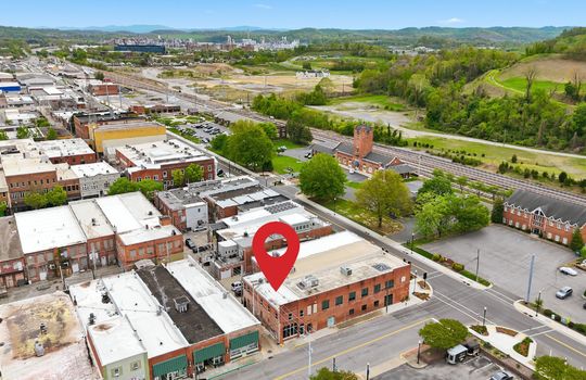 aerial view of commercial space for lease, location pin, main street, road, nearby businesses, mountain views,railroad, brick exterior, street parking, location pin