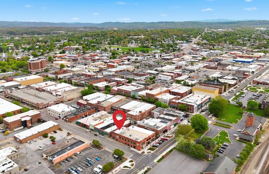 aerial view of commercial space for lease, location pin, main street, road, nearby businesses, mountain views,railroad, brick exterior, street parking, location pin