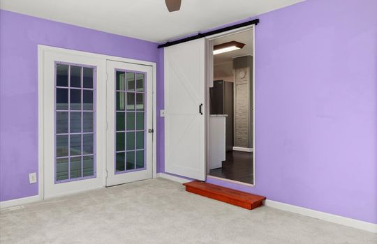 primary bedroom, carpet, door to utility room, barn door into kitchen