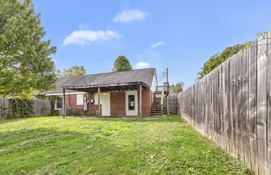 back yard, covered patio, exterior door, stairs to balcony, brick exterior, fencing