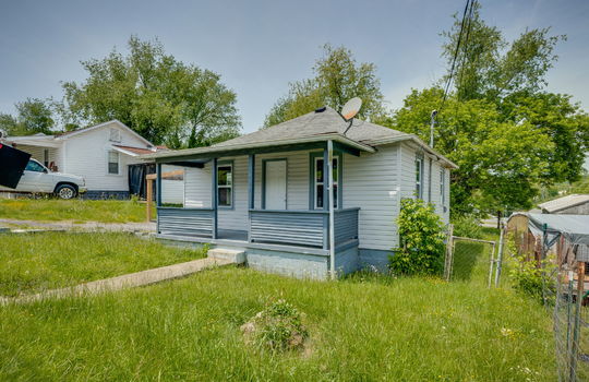 bungalow/cottage, yard, sidewalk, driveway, covered front porch, front door, vinyl siding, shingle roof