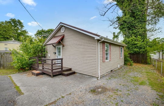 cottage, vinyl siding, front door, front porch, windows, gravel driveway, fencing
