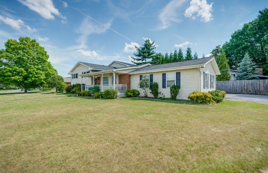 right side view of home, tri-level home, vinyl siding, brick, front yard, driveway, front porch, covered front porch, front door, fencing