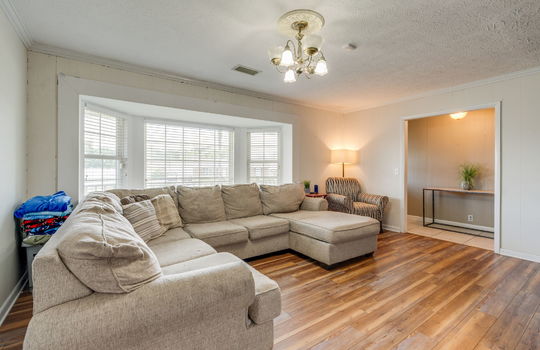 living room, bay windows, hardwood flooring, view into entry hallway