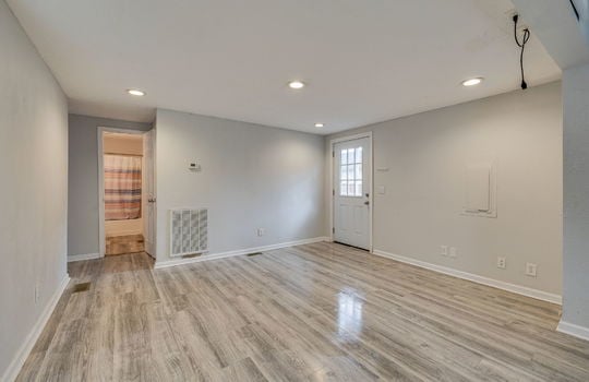 living room, front door, recessed lighting, laminate flooring, doorway to bathroom,