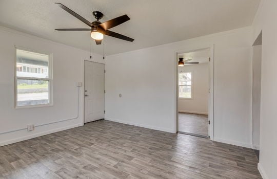 living room, front door, window, laminate flooring, ceiling fan, door to bedroom