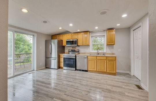 kitchen, laminate flooring, recessed lighting, stainless appliances, refrigerator, stove, dishwasher, built-in microwave, cabinets, countertops, sink, sliding door to side porch